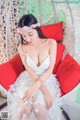A woman in a white dress sitting on a red chair.