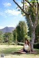 A woman sitting under a tree in a park.