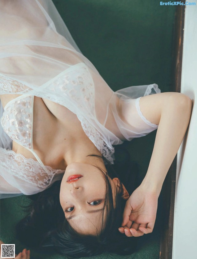 A woman laying on the floor in a white lingerie.