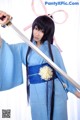 A woman in a blue kimono holding a sword.