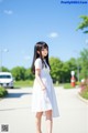 A woman in a white dress is walking down the street.