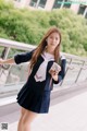 A woman in a school uniform holding a drink.