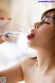 A woman with glasses drinking water from a bottle.