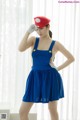 A woman in a blue dress and a red hat.