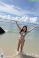 A woman in a blue bikini standing in the ocean.