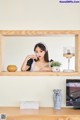 A woman sitting on top of a wooden shelf next to a television.