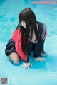 A woman in a sailor outfit crouching down in a pool.