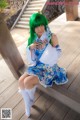 A woman with green hair sitting on a wooden bench.