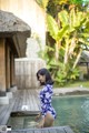 A woman in a blue and white floral swimsuit standing by a pool.