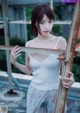 A woman in a white tank top leaning against a metal railing.