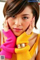 A woman in a yellow top and pink gloves.