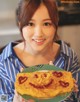 A woman holding a plate with a smiley face on it.