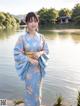 A woman in a blue kimono standing by a lake.