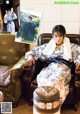 A woman in a kimono sitting on a couch in a living room.