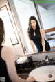 A woman in a black dress standing in front of a mirror.