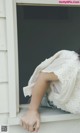 A woman in a white dress sitting on a window sill.