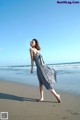 A woman walking on the beach in a black and white dress.