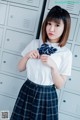 A woman in a school uniform standing in front of lockers.