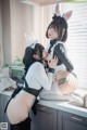 A couple of women in bunny costumes sitting on top of a kitchen counter.