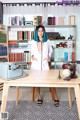 A woman with blue hair standing in front of a desk.