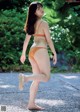 A woman in an orange bikini walking down a road.