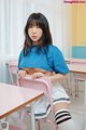 A woman sitting at a desk in a classroom.