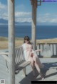 A woman sitting on a wooden bench on a beach.