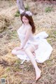 A woman in a white dress sitting on a pile of hay.