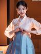 A woman in a blue and white hanbok is posing for a picture.