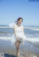 A woman in a wedding dress is walking in the water.