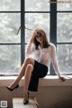 A woman sitting on a window sill with her legs crossed.