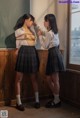 Two young women in school uniforms standing next to each other.