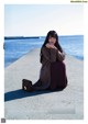 A woman sitting on the edge of a pier next to the ocean.