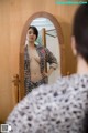 A woman standing in front of a mirror looking at herself in the mirror.