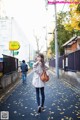 A woman walking down a street with a brown bag.