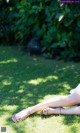 A woman is sitting on the grass with her legs crossed.